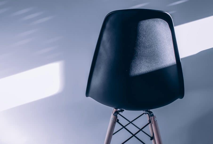 a black chair sitting on top of a wooden stand