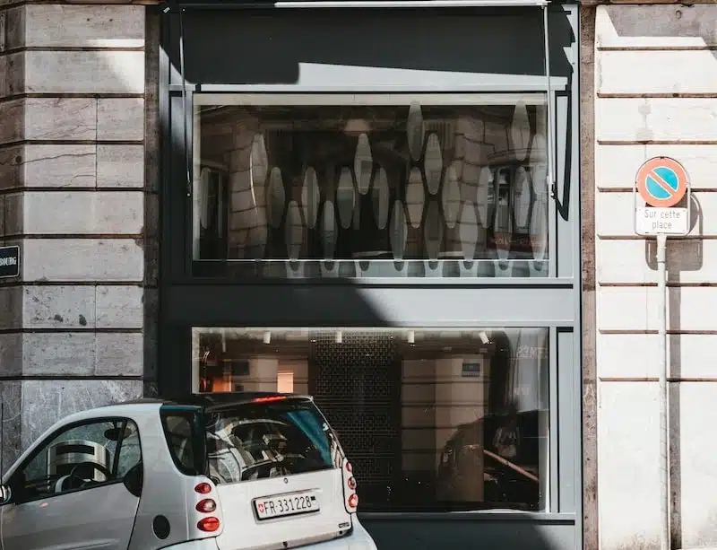 white 5 door hatchback parked beside brown brick building during daytime